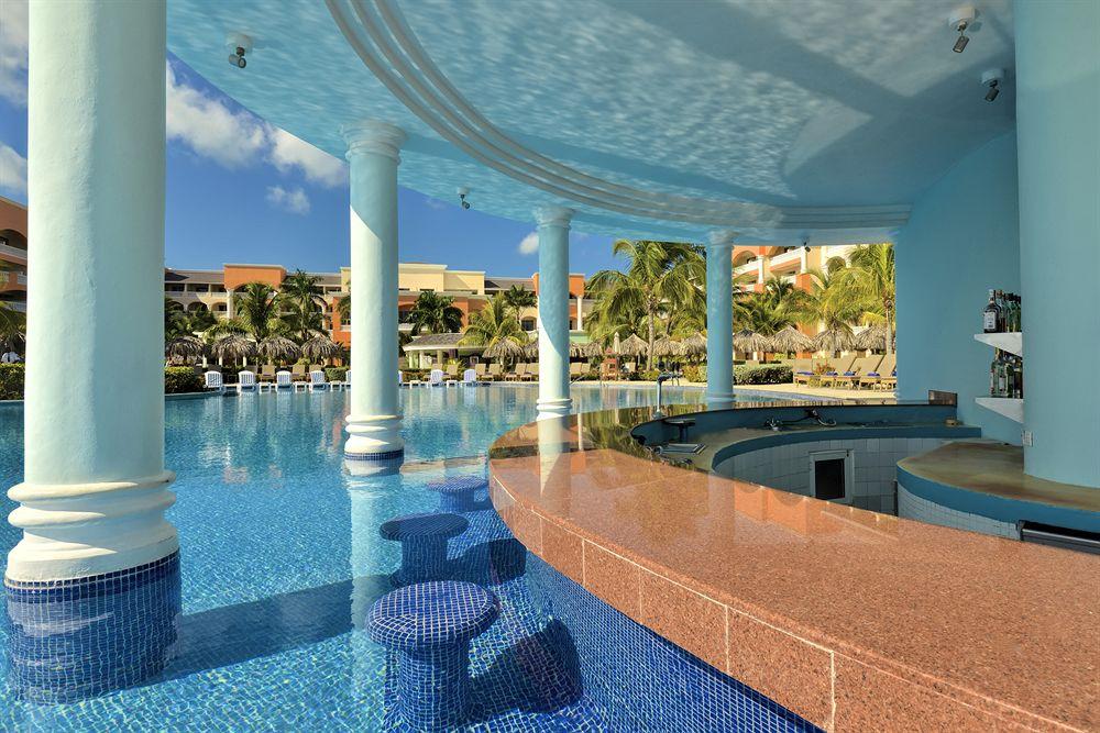 Barbereich des Pools im Iberostar Selection Rose Hall Suites Hotel mit blauen Stühlen und braunem Tresen.