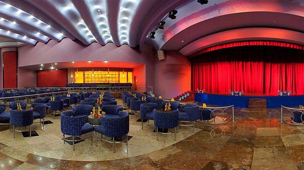 Lobby-Lounge des Iberostar Selection Rose Hall Suites Hotels mit blauen Stühlen und roter Bühne.