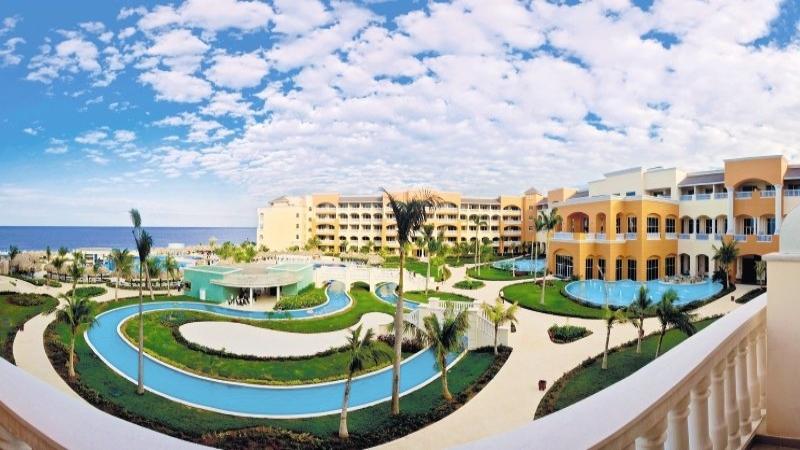Außenansicht des Iberostar Selection Rose Hall Suites Resorts mit Pools und Palmen.