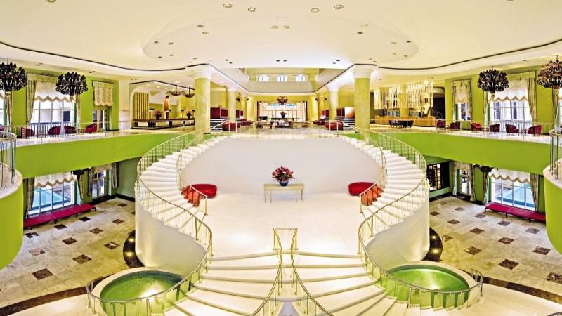 Innenbereich des Iberostar Selection Rose Hall Suites Hotels mit einer spiralförmigen Treppe und Blumen.
