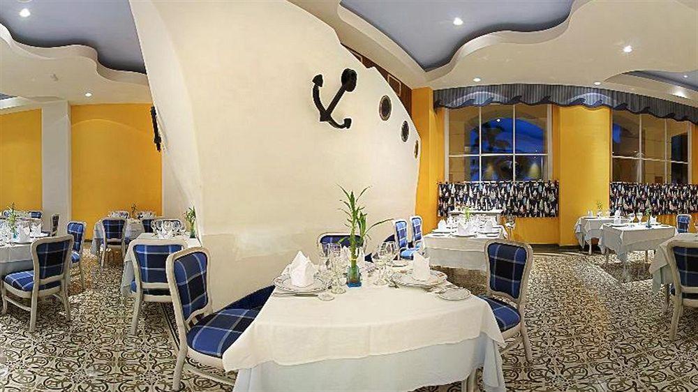 Innenansicht des Restaurants im Iberostar Selection Rose Hall Suites Hotel mit blauen Stühlen und weißen Tischdecken.