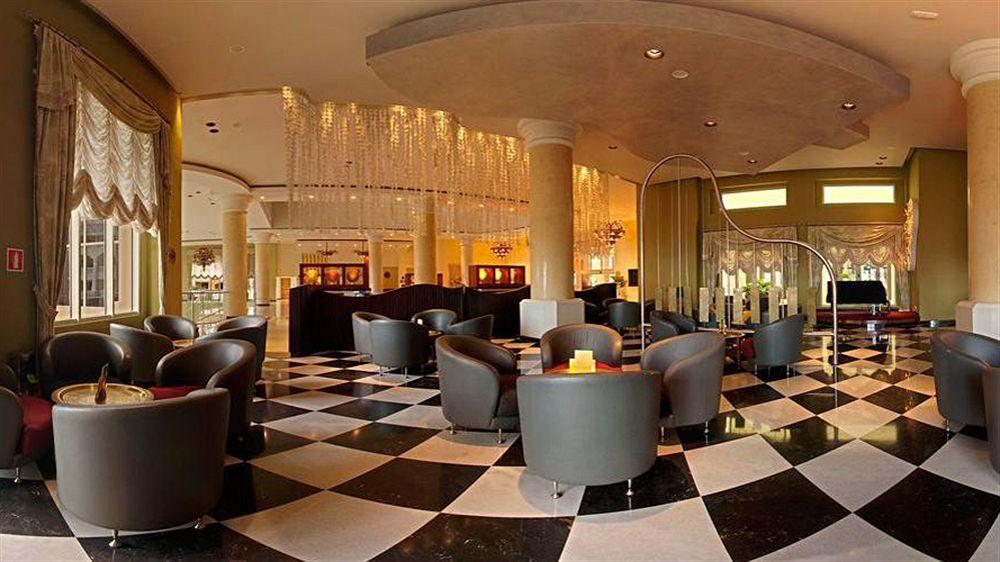 Lobby des Iberostar Selection Rose Hall Suites Hotels mit schwarzen und weißen Fliesenboden und mehreren Sitzgelegenheiten.