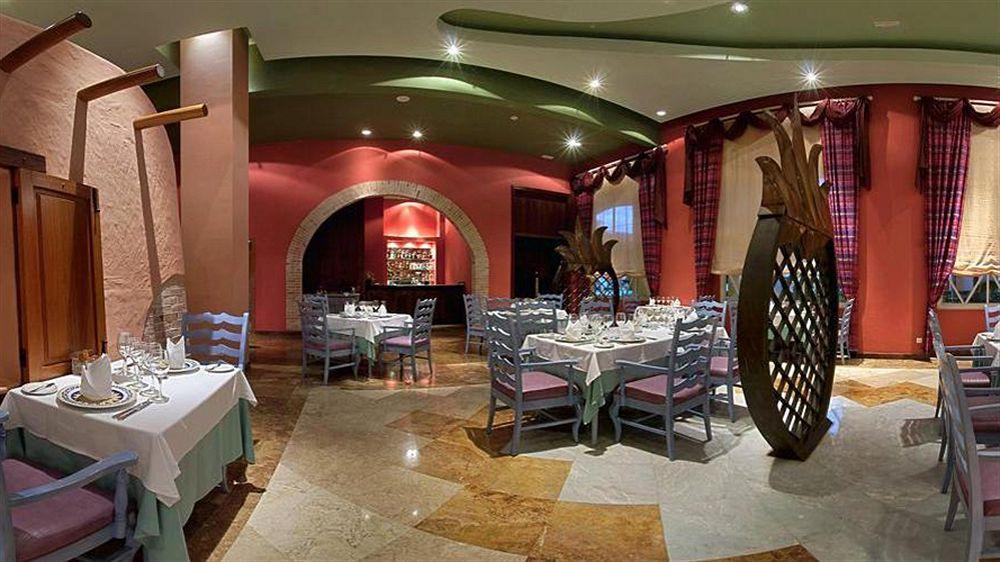 Innenansicht des Restaurants im Iberostar Selection Rose Hall Suites Hotel mit gedeckten Tischen und Stühlen.