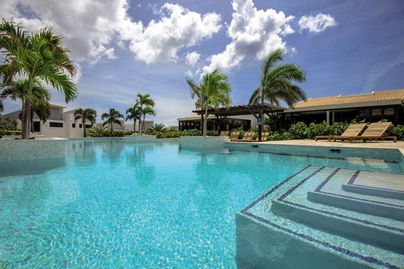 Außenpool des Blue Bay Curacao Golf & Beach Resort mit Sonnenliegen und Palmen