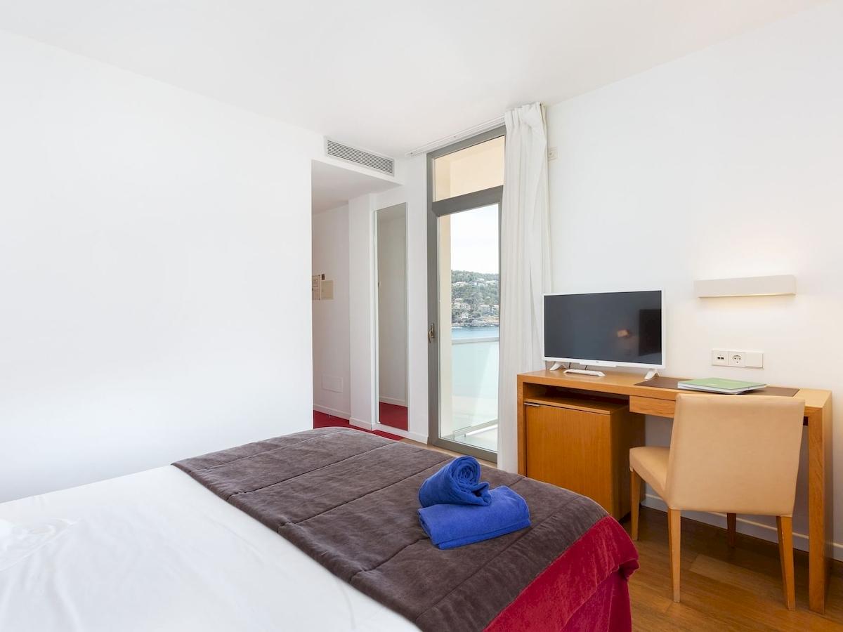Hotelzimmer im Aimia Hotel mit Blick auf das Meer, mit Bett, Schreibtisch und Fernseher.