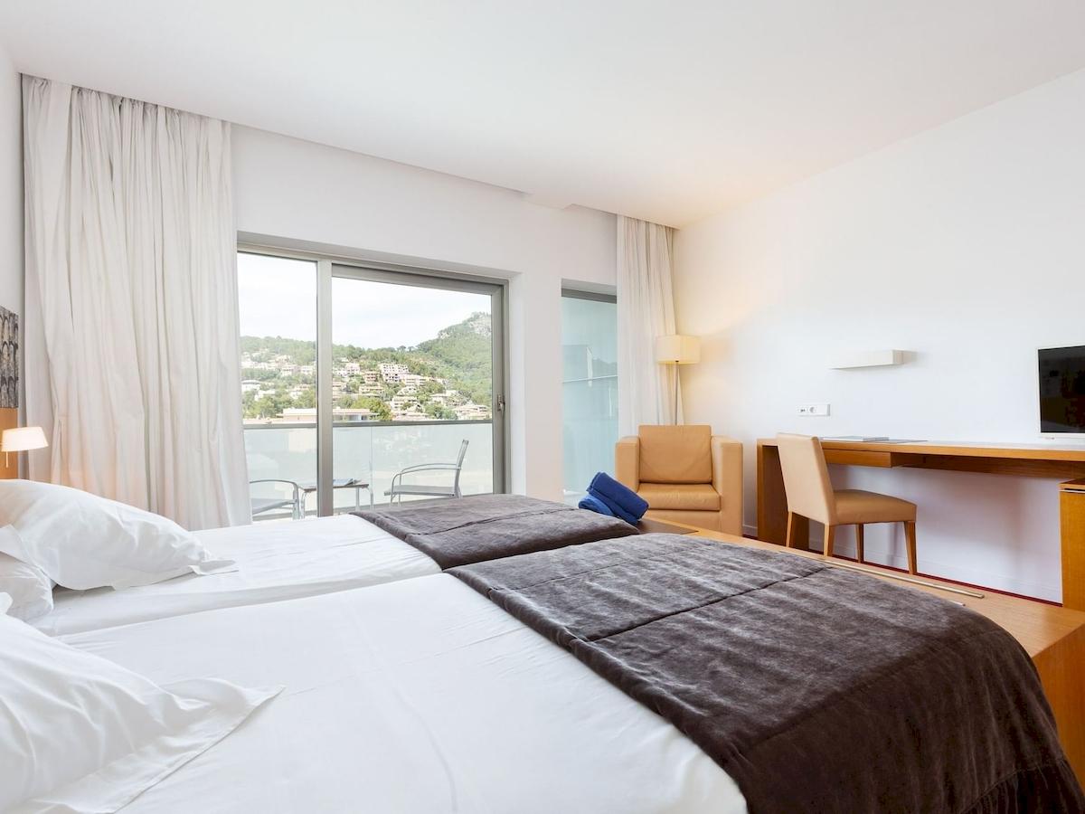 Schlafzimmer im Aimia Hotel mit zwei Betten, Blick auf die Stadt und Möbeln.