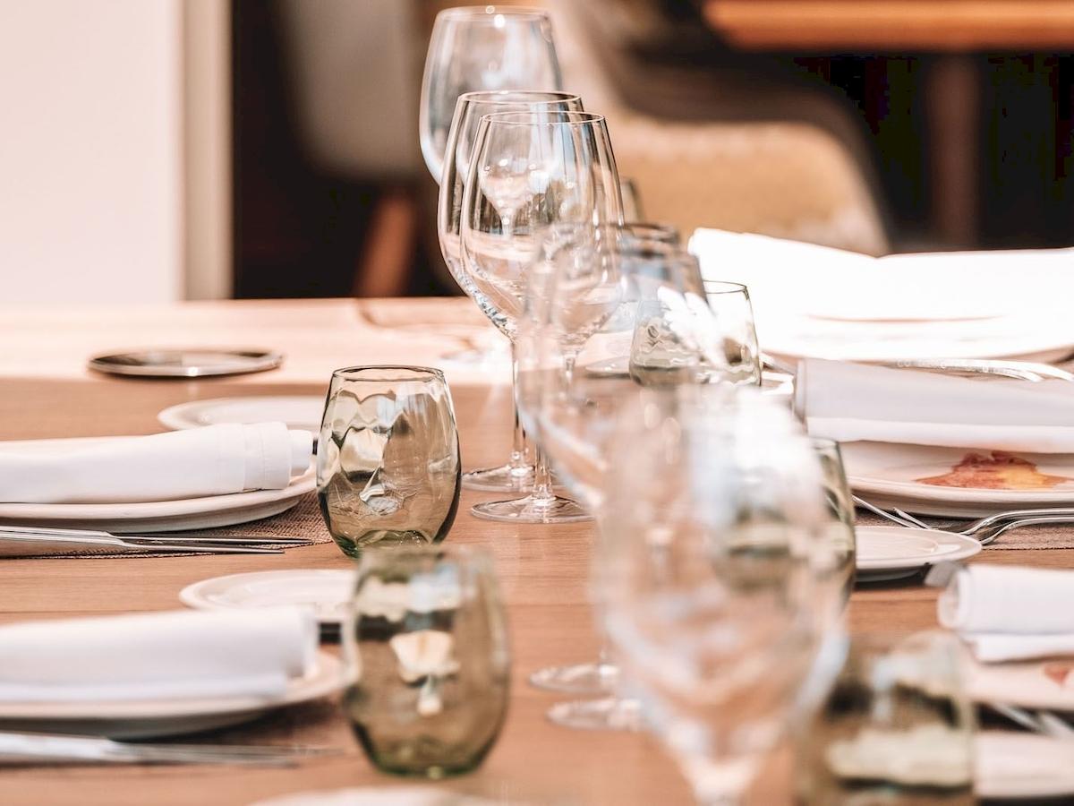 Gedeckter Tisch im Aimia Hotel mit Gläsern, Tellern und Servietten.