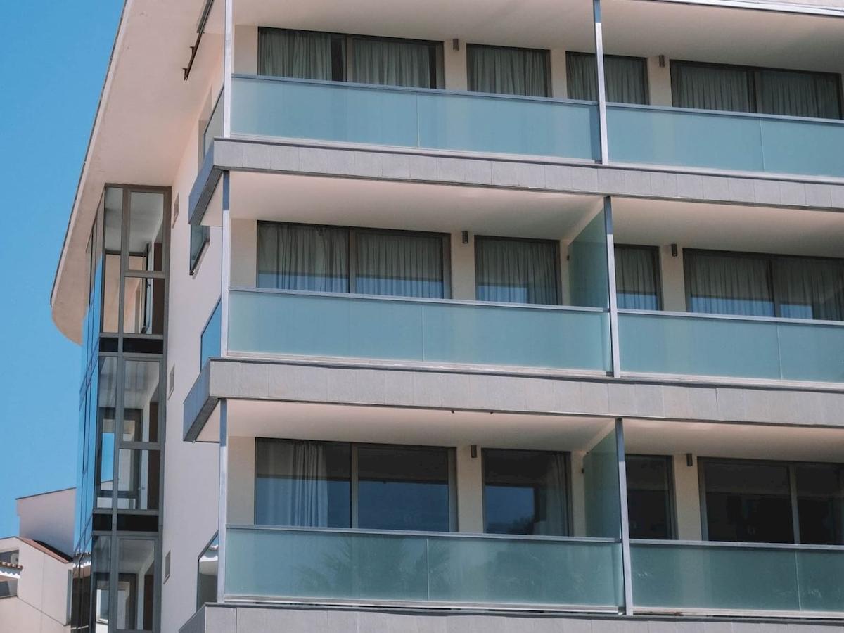 Außenansicht des Aimia Hotels mit mehreren Stockwerken und blauen Glasbalkonen.