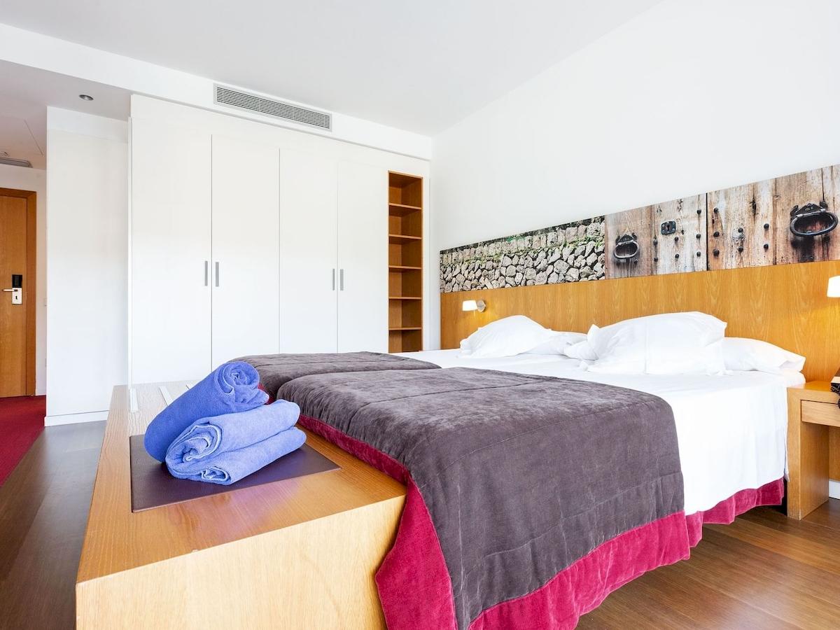 Schlafzimmer im Aimia Hotel mit zwei Betten, weißen Kissen und blauen Handtüchern.