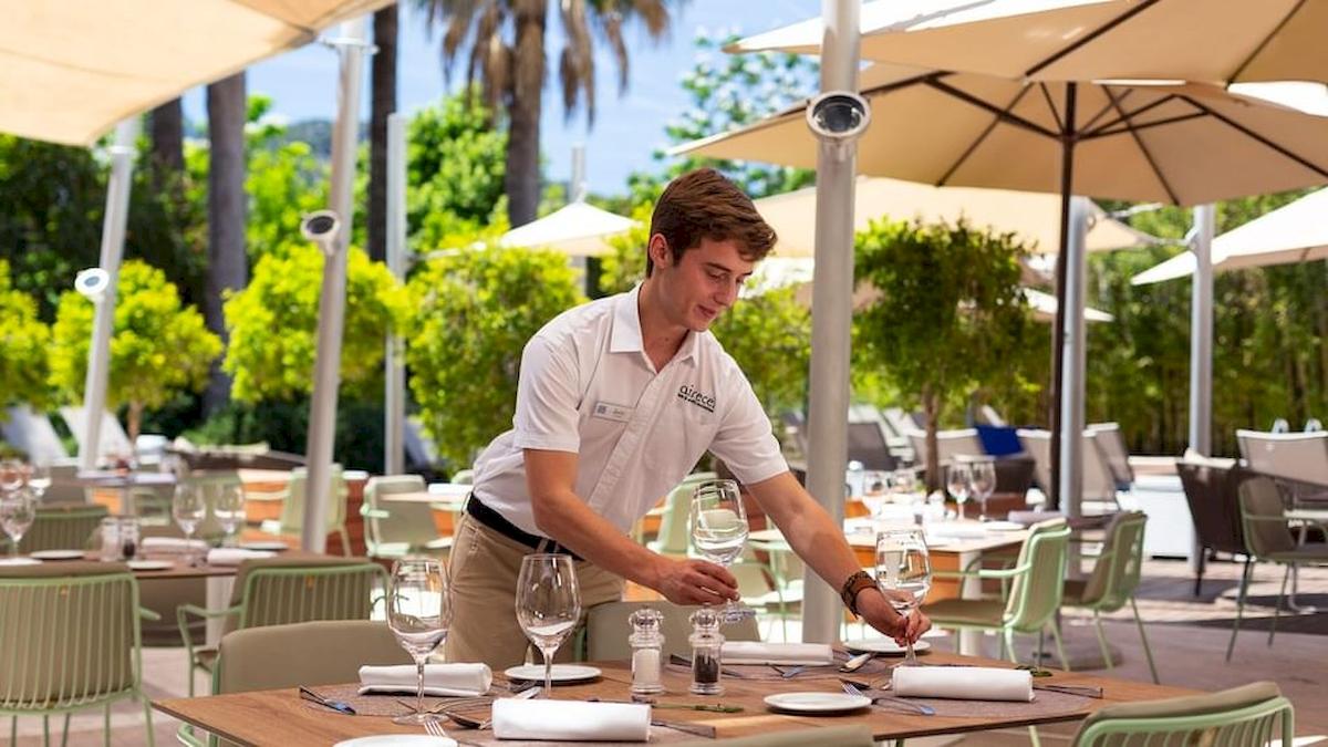 Ein Kellner im Aimia Hotel bereitet einen Tisch im Freien vor.