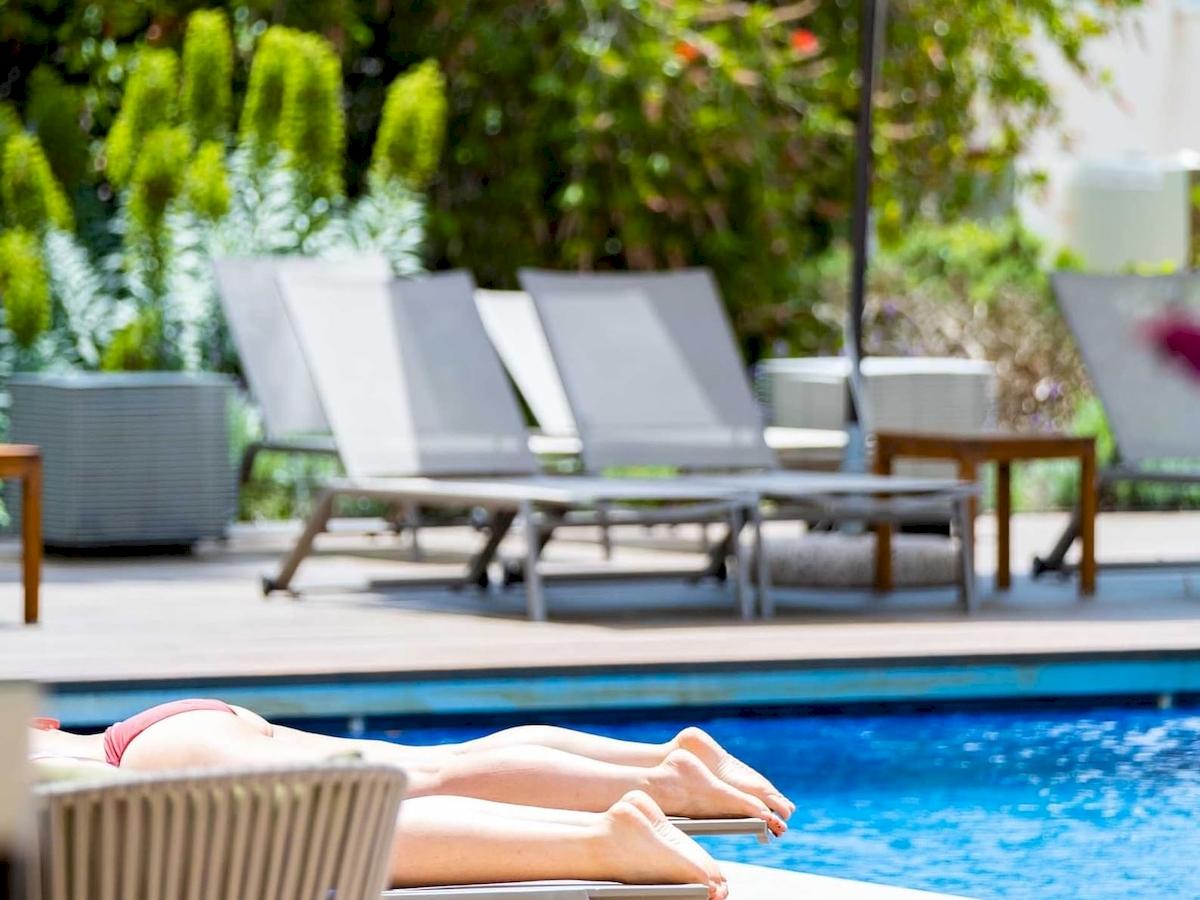 Personen liegen auf Liegestühlen am Pool des Aimia Hotels