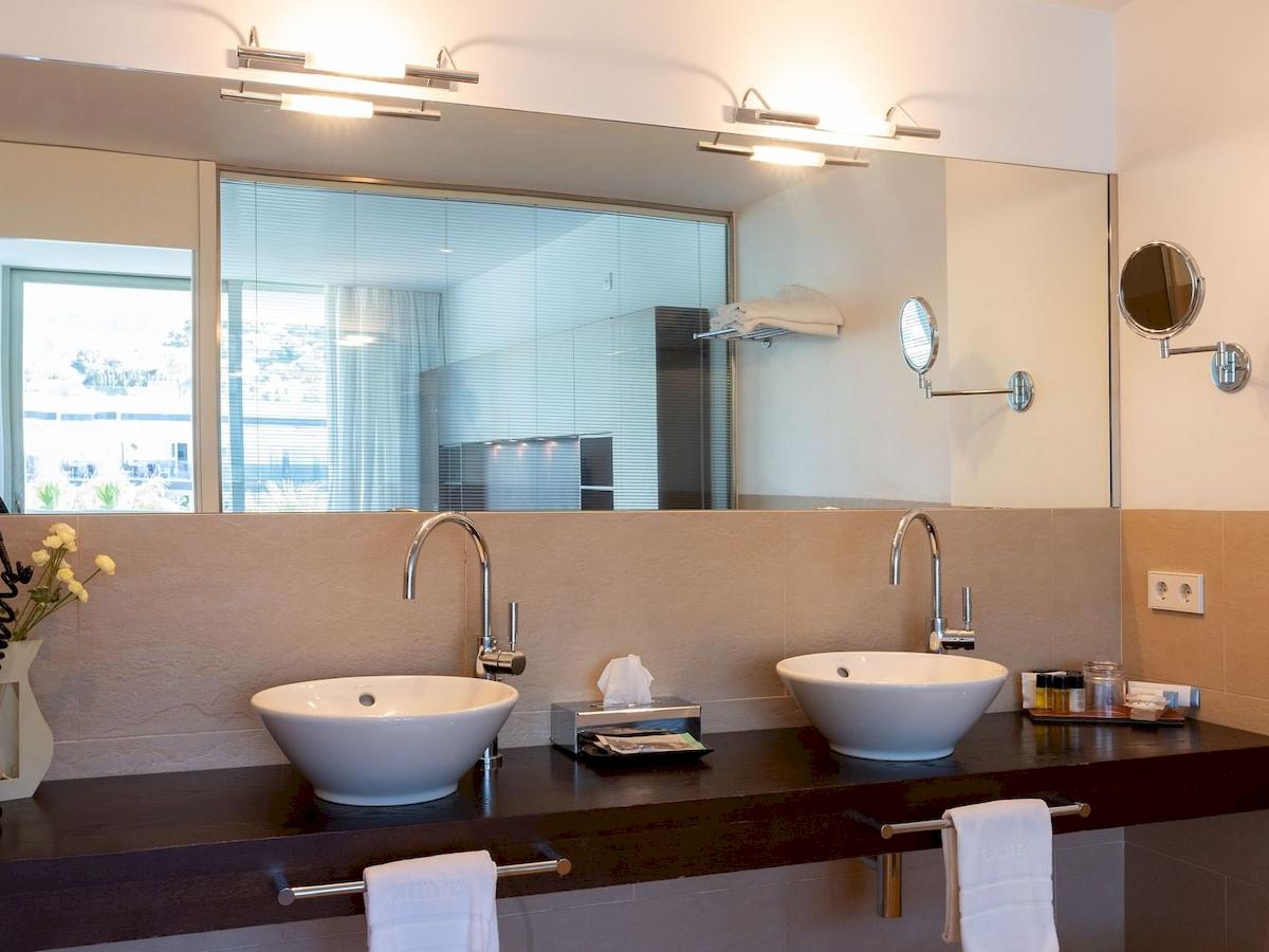 Badezimmer im Aimia Hotel mit zwei Waschbecken und Spiegeln.