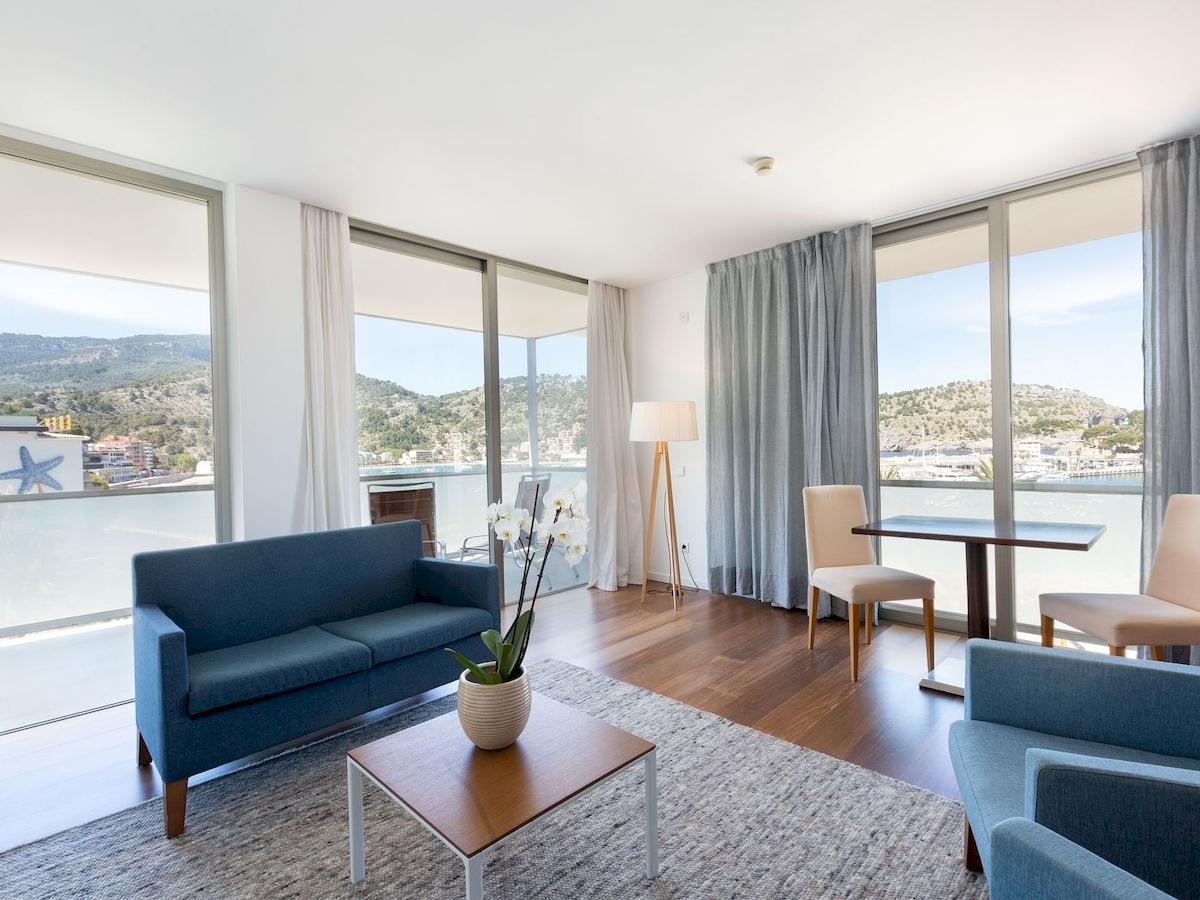 Wohnzimmer des Aimia Hotels mit Blick auf das Meer, voll möbliert mit Sofas, Tisch, Stühlen und einer Pflanze.