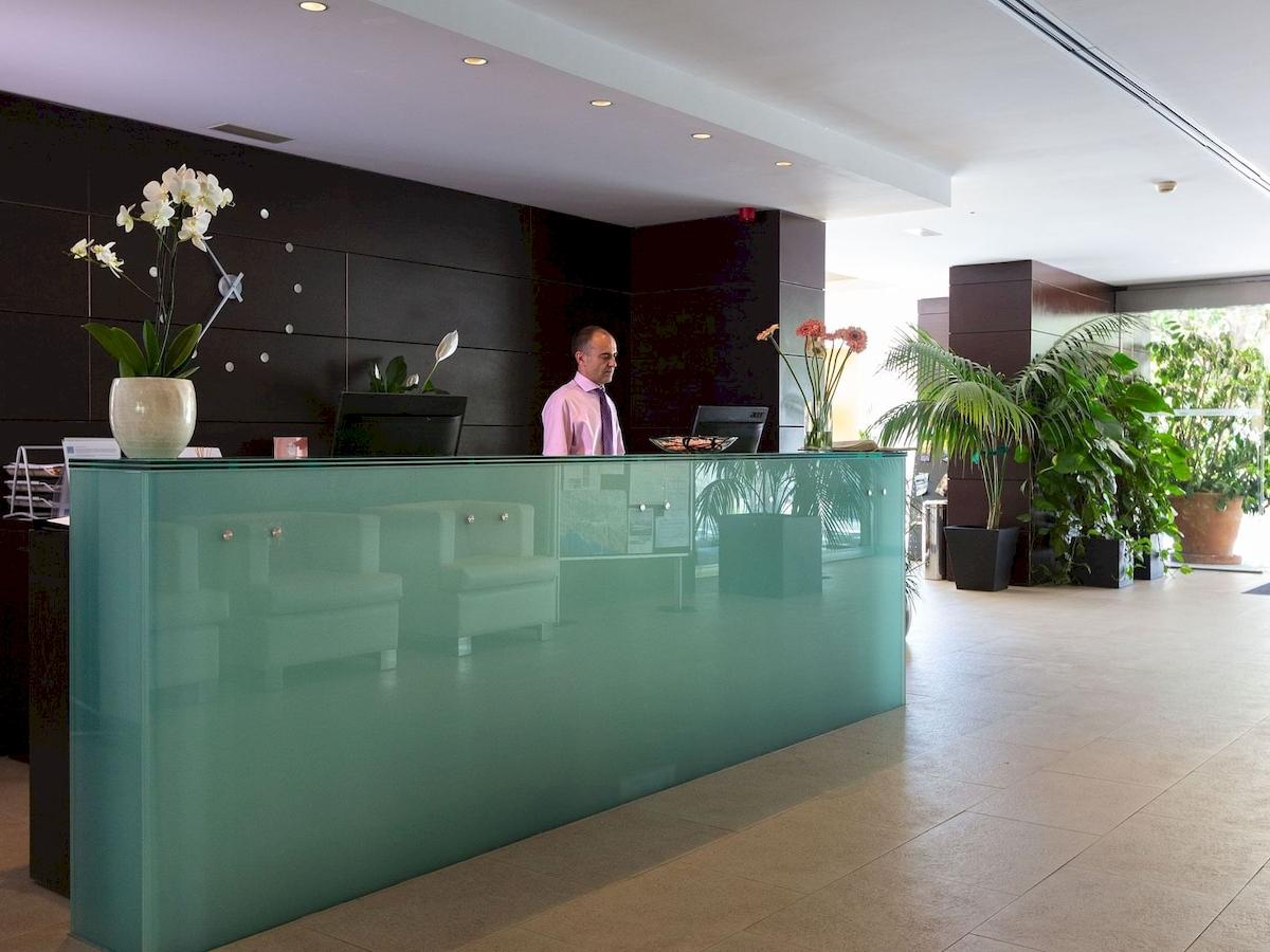 Empfangsbereich mit einem Mann in einem rosa Hemd im Aimia Hotel