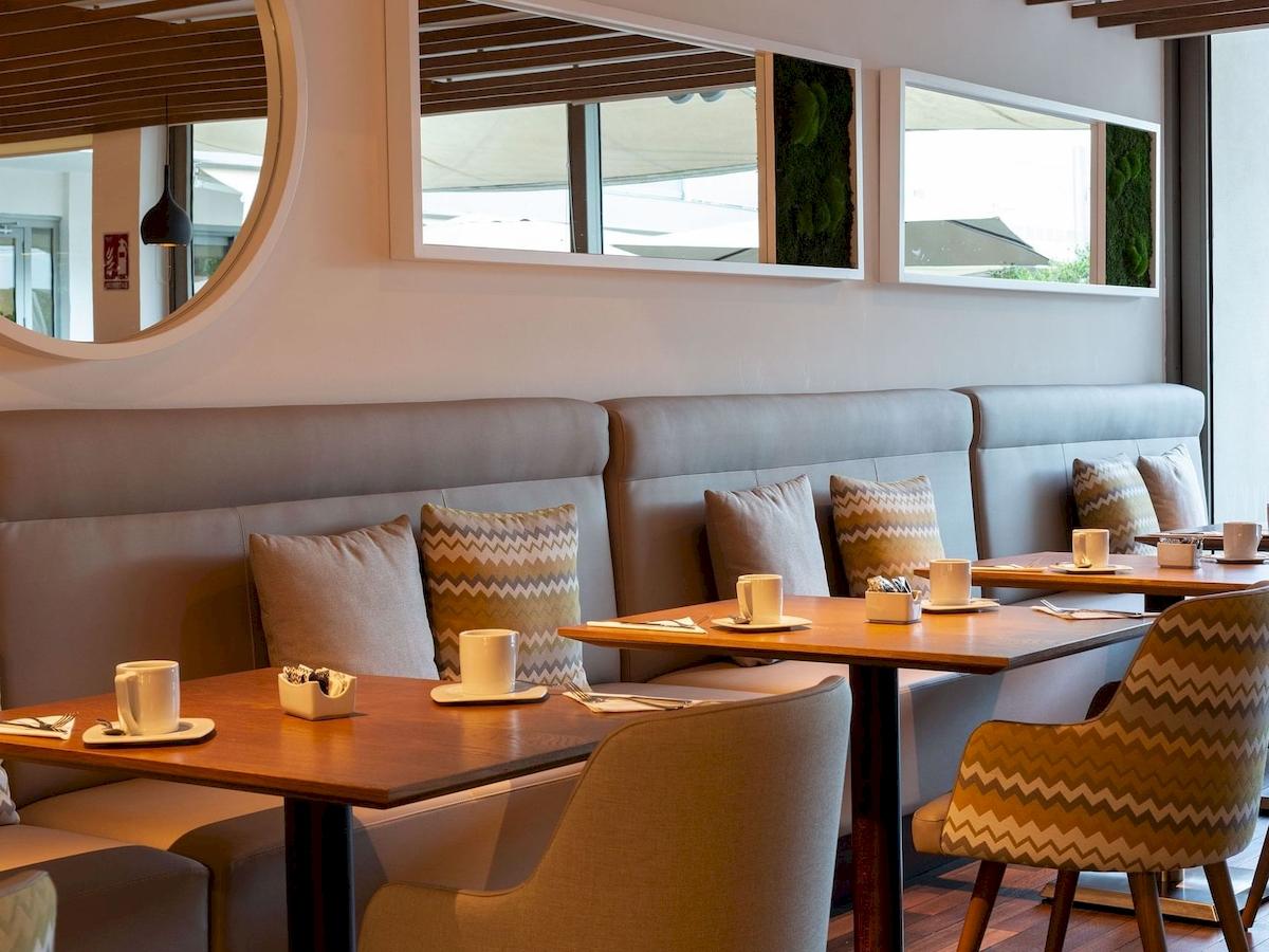 Innenbereich des Aimia Hotels, Tisch und Stühle in einem Restaurant mit modernen Möbeln und Dekoration.