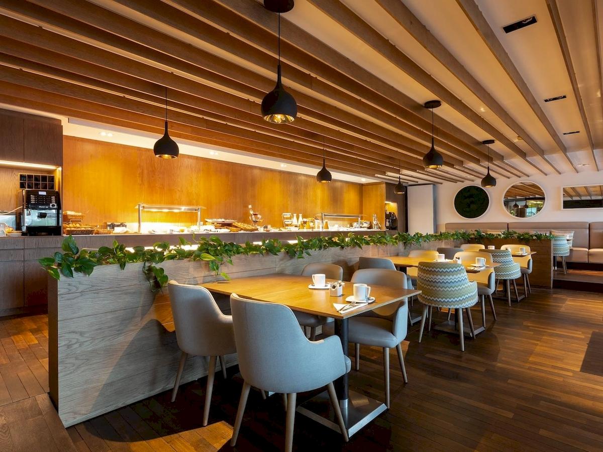 Innenansicht des Restaurants im Aimia Hotel mit Holzböden und modernen Möbeln.