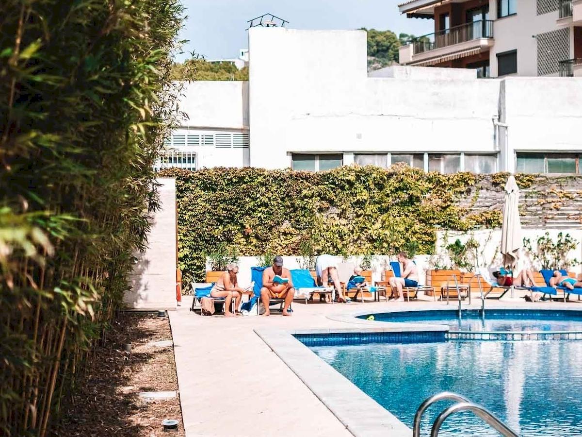 Schwimmbadbereich mit mehreren Personen, die sich entspannen, vor dem Aimia Hotel