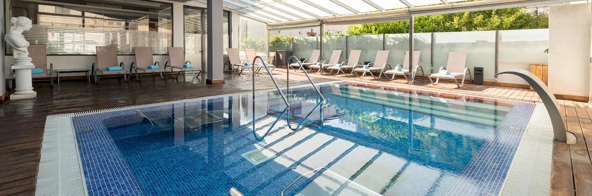 Poolbereich im Nautic Hotel & Spa mit Loungestühlen und Glasdach