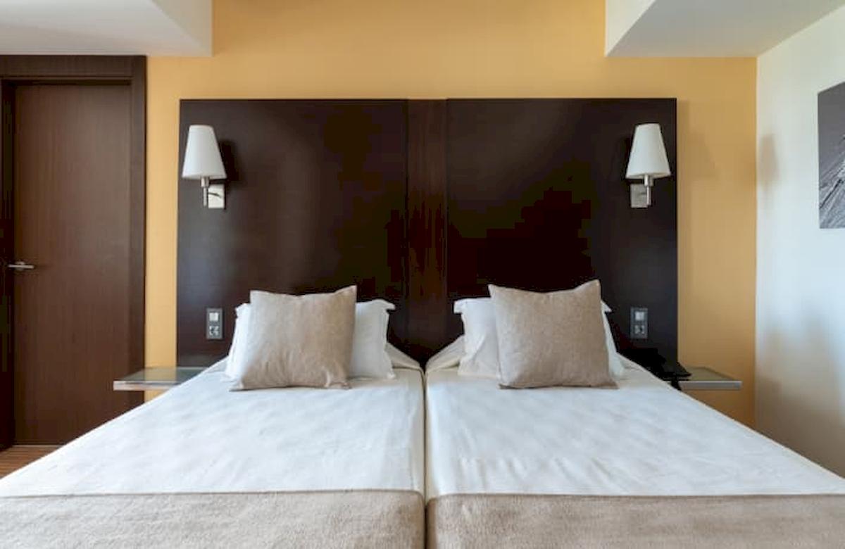 Doppelbett im Hotelzimmer im Nautic Hotel & Spa mit weißen Laken und Kissen.