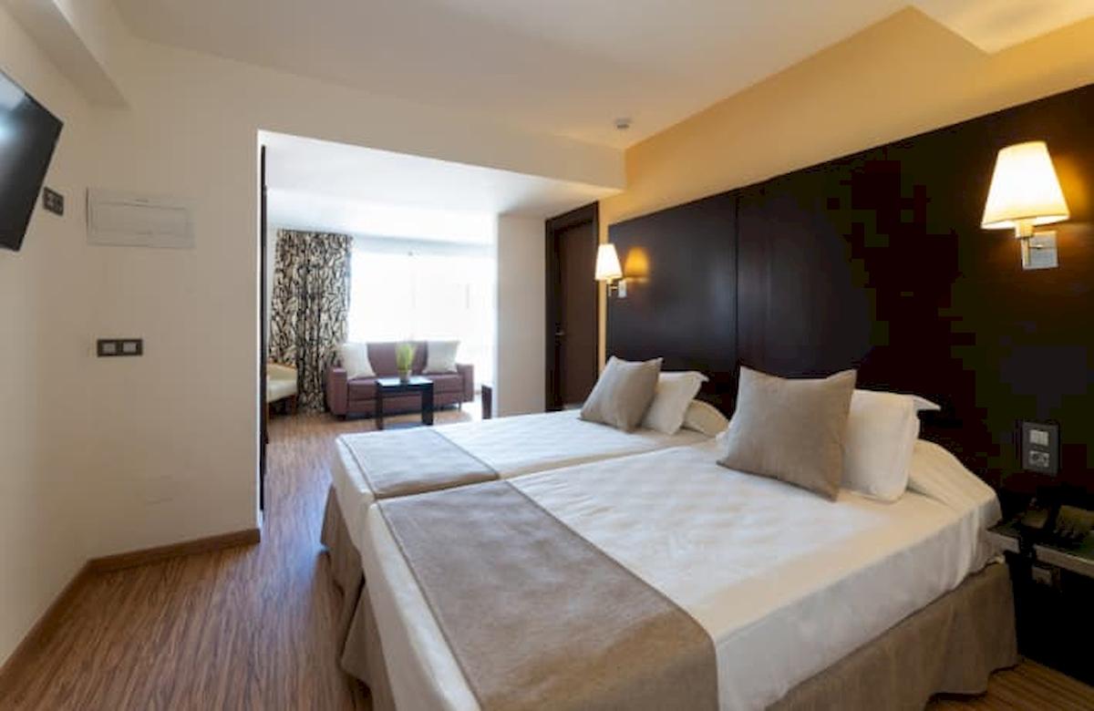 Doppelbettzimmer im Nautic Hotel & Spa mit Blick auf ein Wohnzimmer.