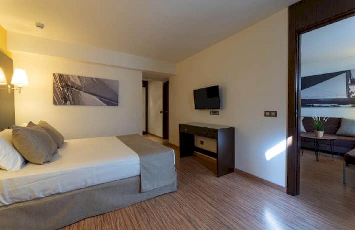 Schlafzimmer im Nautic Hotel & Spa mit Doppelbett, Fernseher und Wohnzimmerbereich.