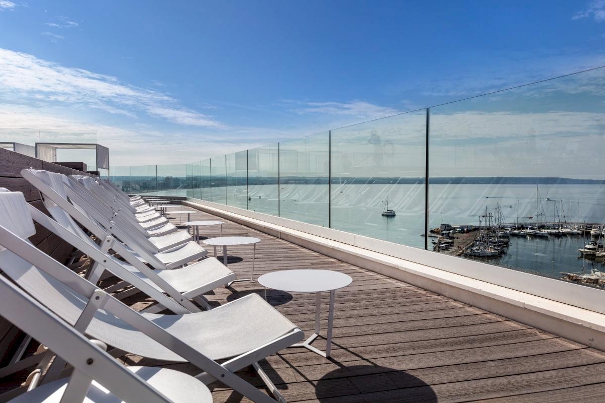 Dachterrasse mit Blick auf den Hafen und weißen Liegestühlen