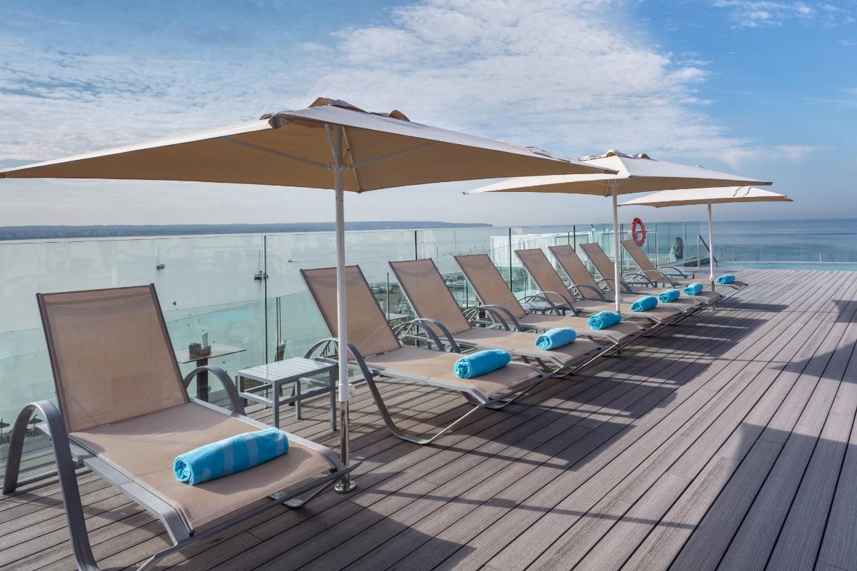 Terrasse des Nautic Hotel & Spa mit Liegen, Sonnenschirmen und Blick auf das Meer.