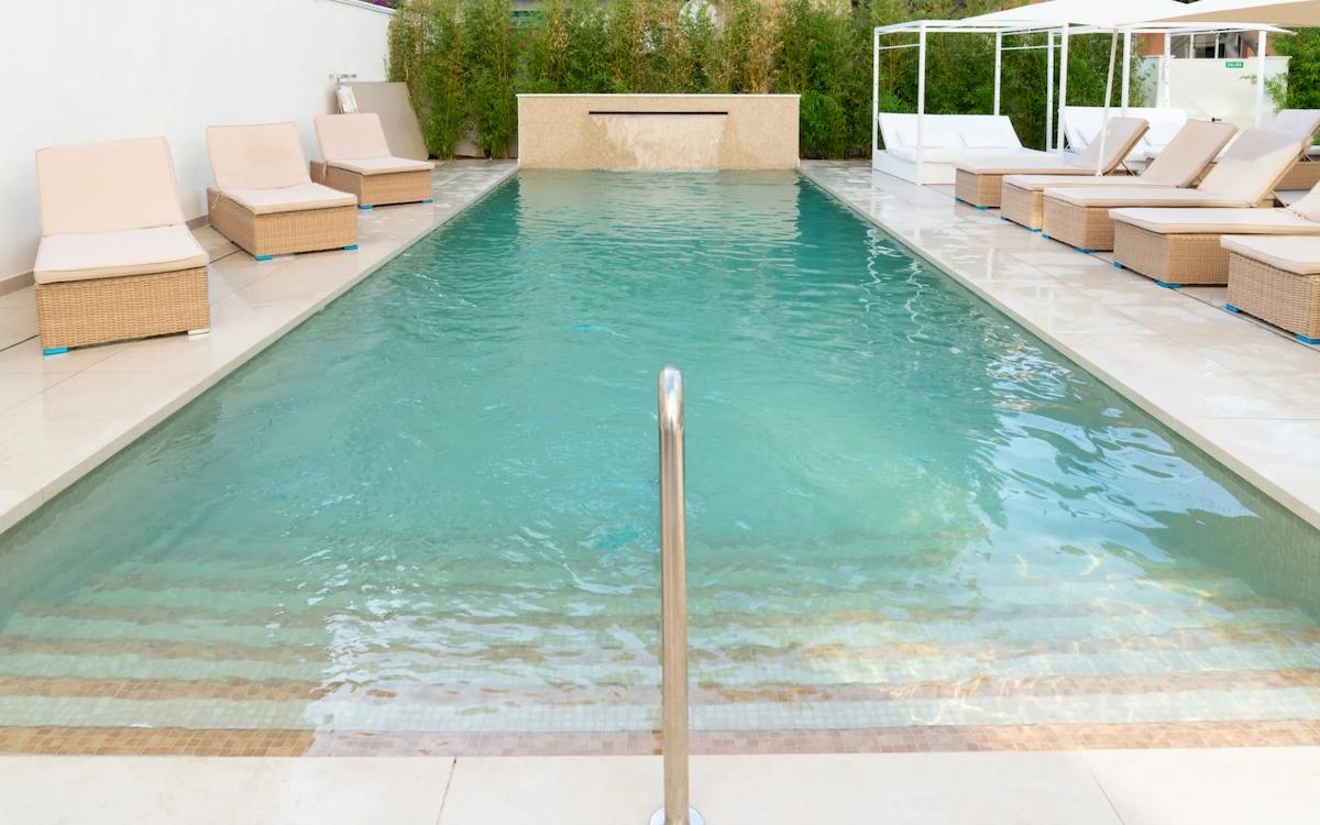 Außenpool des Nautic Hotel & Spa mit Liegen und Sonnenschirmen.