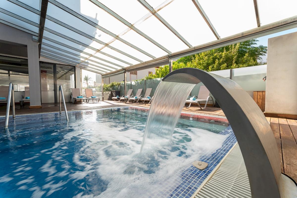 Ein Pool mit Wasserfall im Freien im Nautic Hotel & Spa.