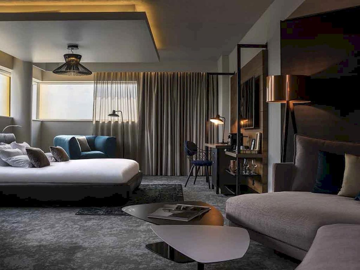 Hotelzimmer im Novotel London Canary Wharf mit Bett, Sofa, Schreibtisch und Fenstern.