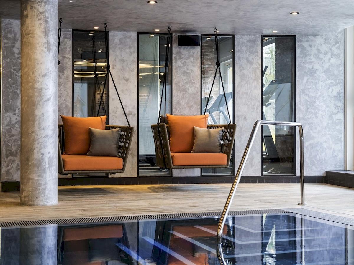 Schwimmbereich im Novotel London Canary Wharf Hotel mit zwei hängenden Liegestühlen und einer Handlauf.