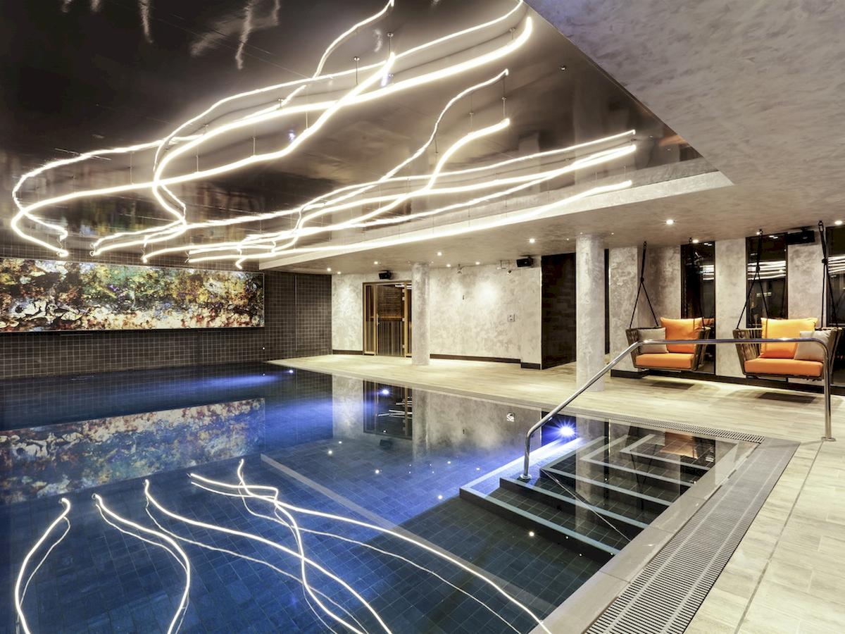 Indoorpool im Novotel London Canary Wharf mit blauem Wasser und leuchtenden Lichtern an der Decke.