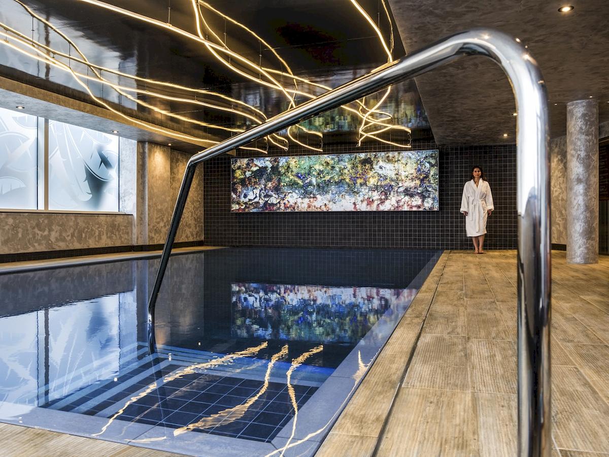 Novotel London Canary Wharf Innenpool mit moderner Beleuchtung und Kunstwerk an der Wand.