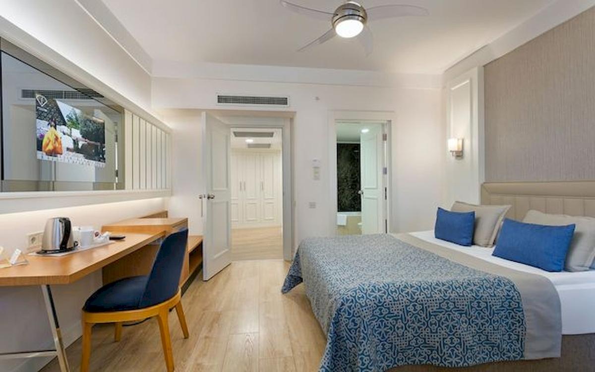 Innenansicht eines Hotelzimmers im Limak Atlantis Deluxe Hotel & Resort mit Bett, Schreibtisch und Fernseher.