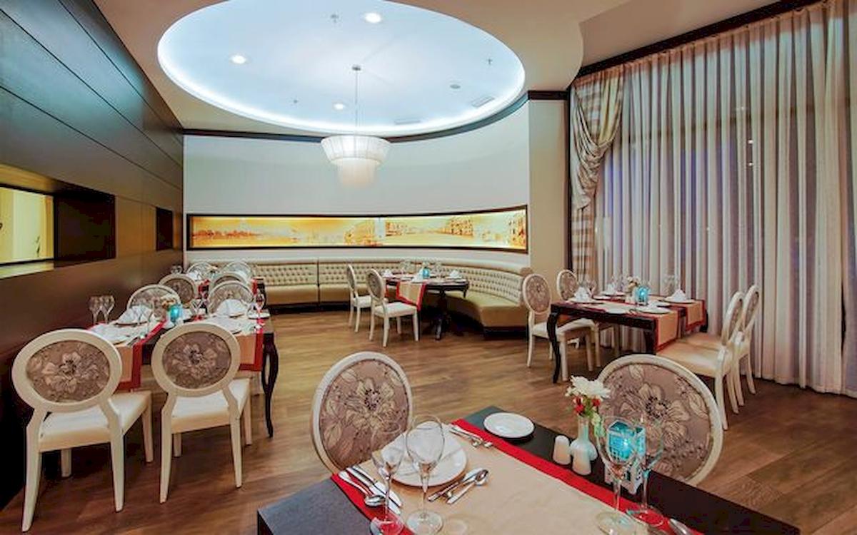 Innenansicht des Restaurants im Limak Atlantis Deluxe Hotel & Resort mit gepolsterten Bänken und runden Tischen.