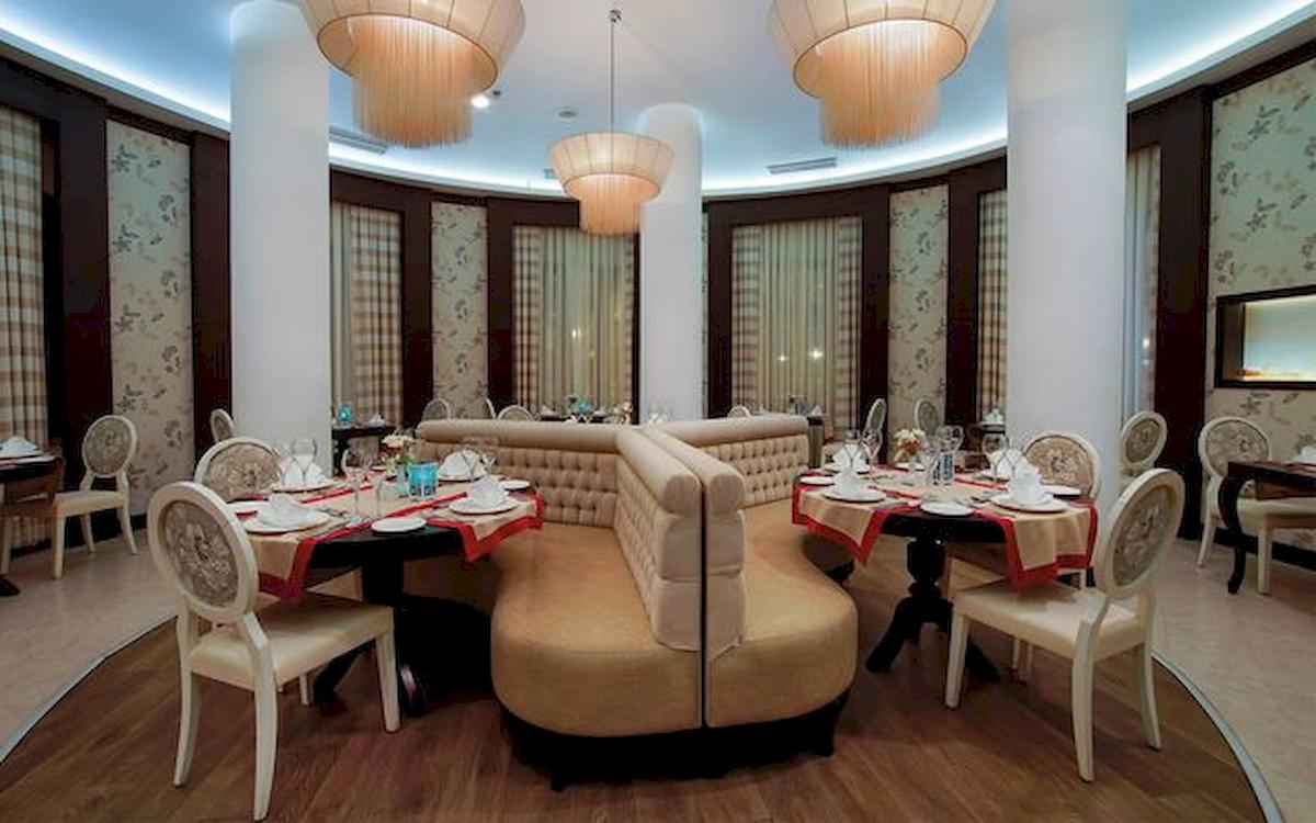 Innenbereich eines Restaurants im Limak Atlantis Deluxe Hotel & Resort mit runden Tischen und gepolsterten Eckbänken.