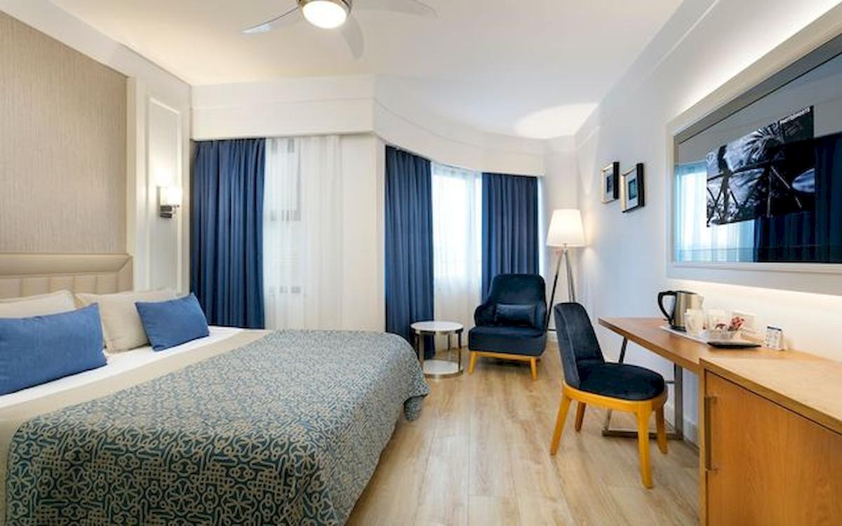 Ein modernes Hotelzimmer mit einem großen Bett, blauen Vorhängen und einem Schreibtisch.