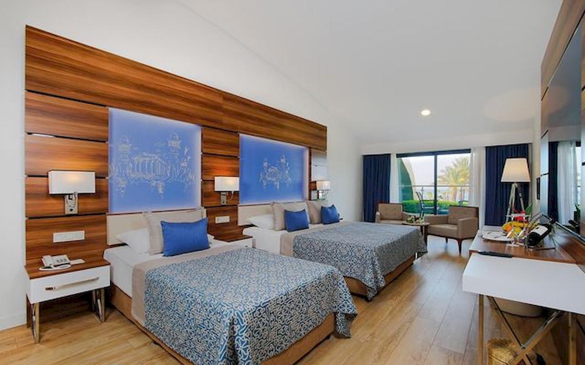 Doppelzimmer im Limak Atlantis Deluxe Hotel & Resort mit zwei Betten, Holzwänden und modernen Möbeln.