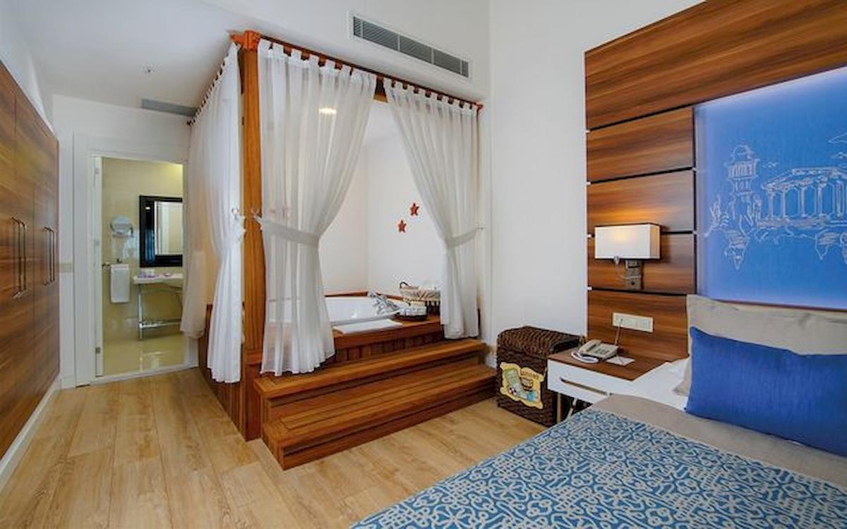 Hotelsuite mit Badewanne, Bett und Holzelementen im Innenraum.
