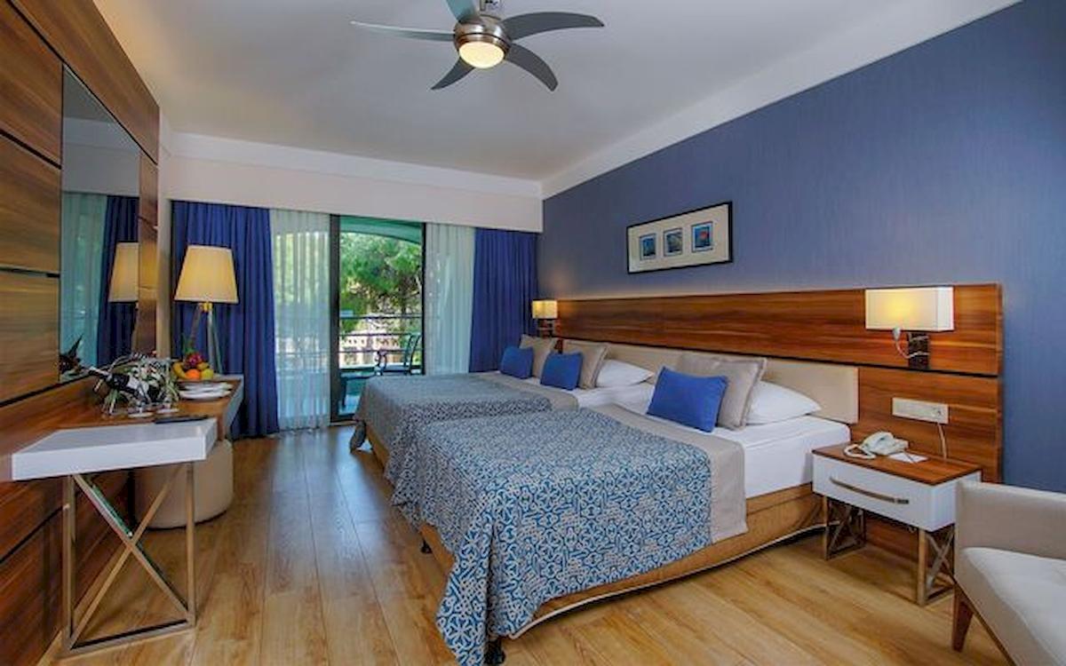 Ein modernes Hotelzimmer mit zwei Betten, blauen Vorhängen und einer Klimaanlage.