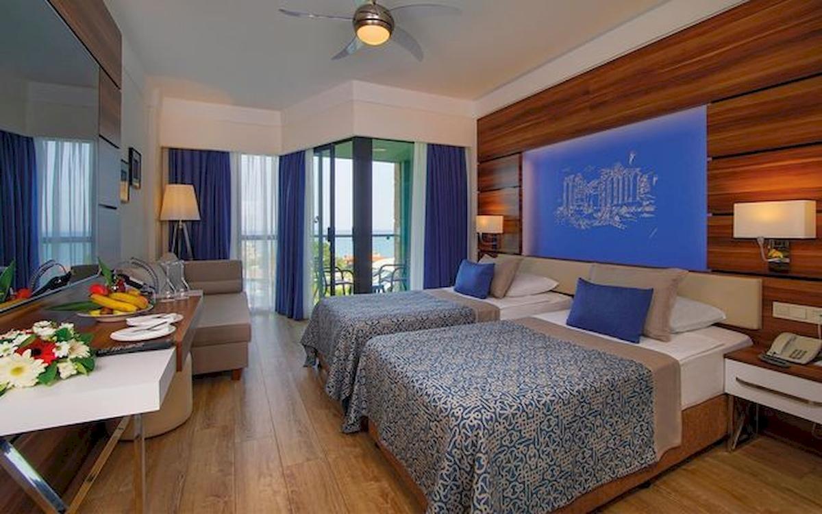 Zwei Betten mit blauen Kissen in einem Hotelzimmer des Limak Atlantis Deluxe Hotel & Resort