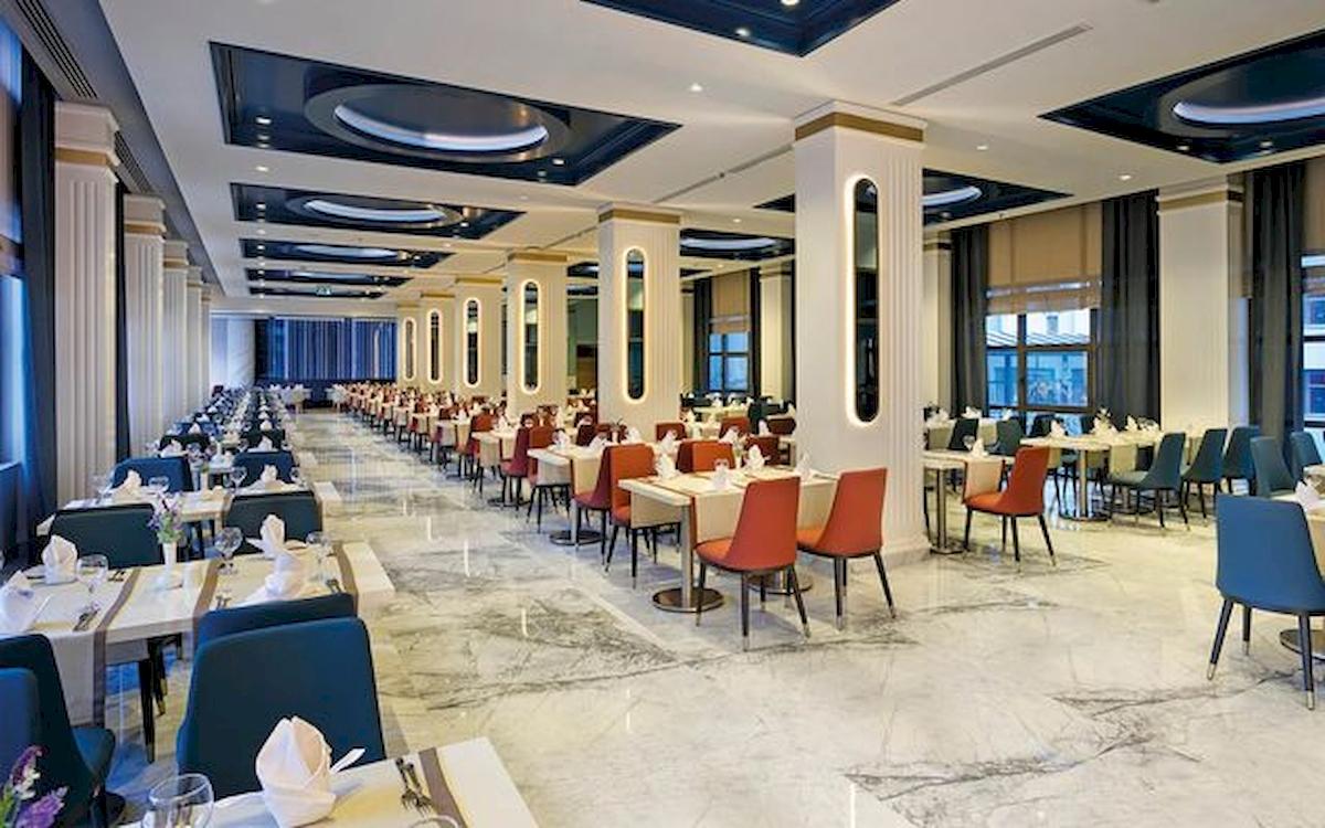 Innenansicht des Restaurants im Limak Atlantis Deluxe Hotel & Resort mit vielen gedeckten Tischen und Stühlen.