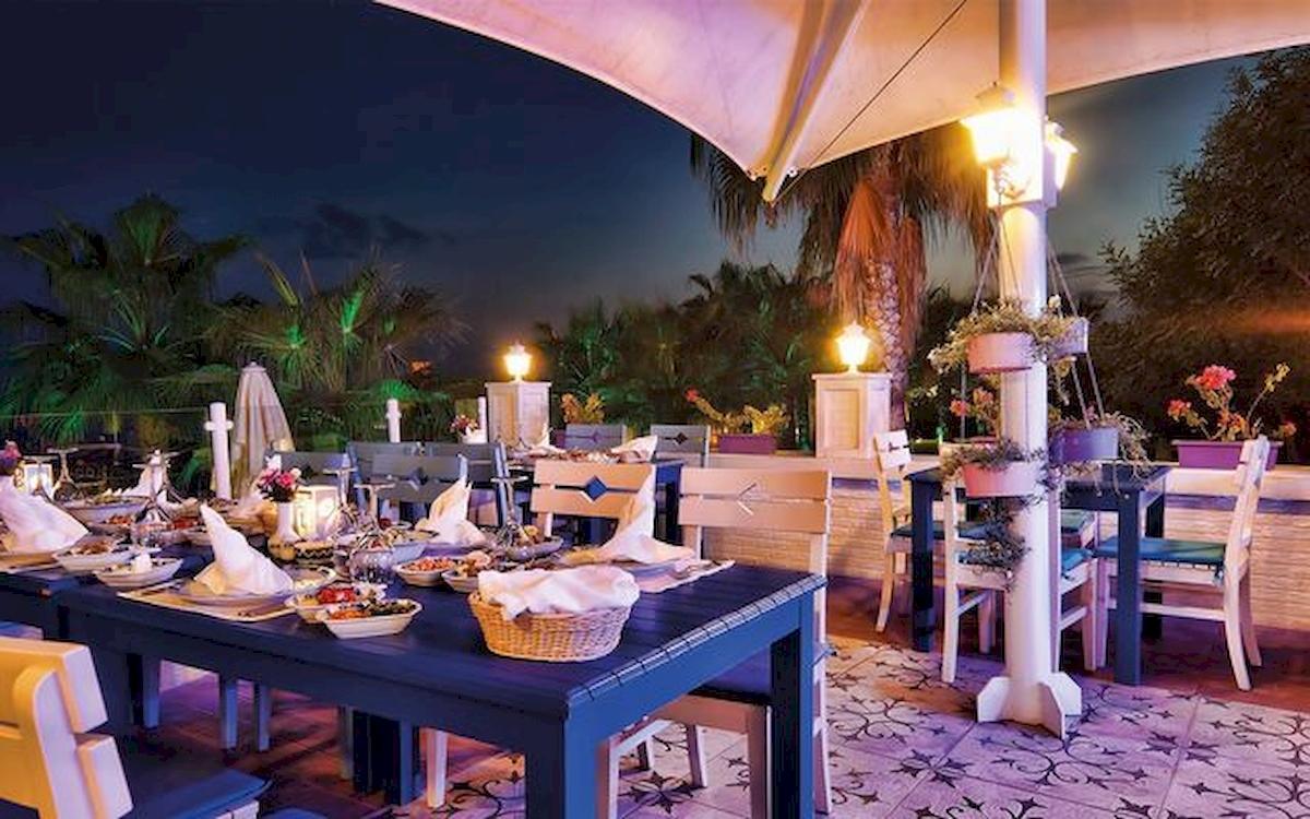 Hotel Terrasse bei Nacht mit vielen Tischdecken und Speisen.