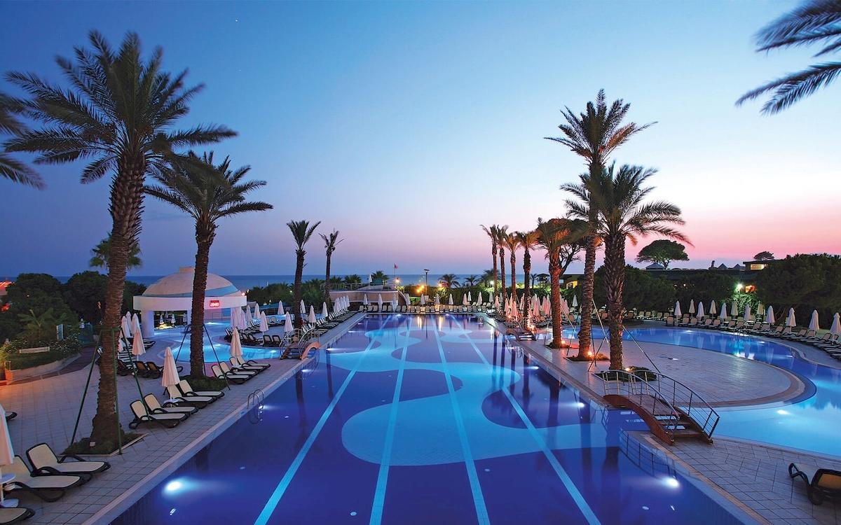 Außenpool des Limak Atlantis Deluxe Hotel & Resort mit Loungeliegen und Palmen