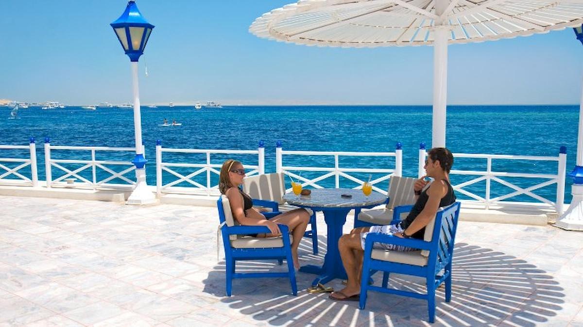 Zwei Gäste sitzen an einem runden Tisch auf der Terrasse des Grand Hotel Hurghada mit Blick auf das Meer.