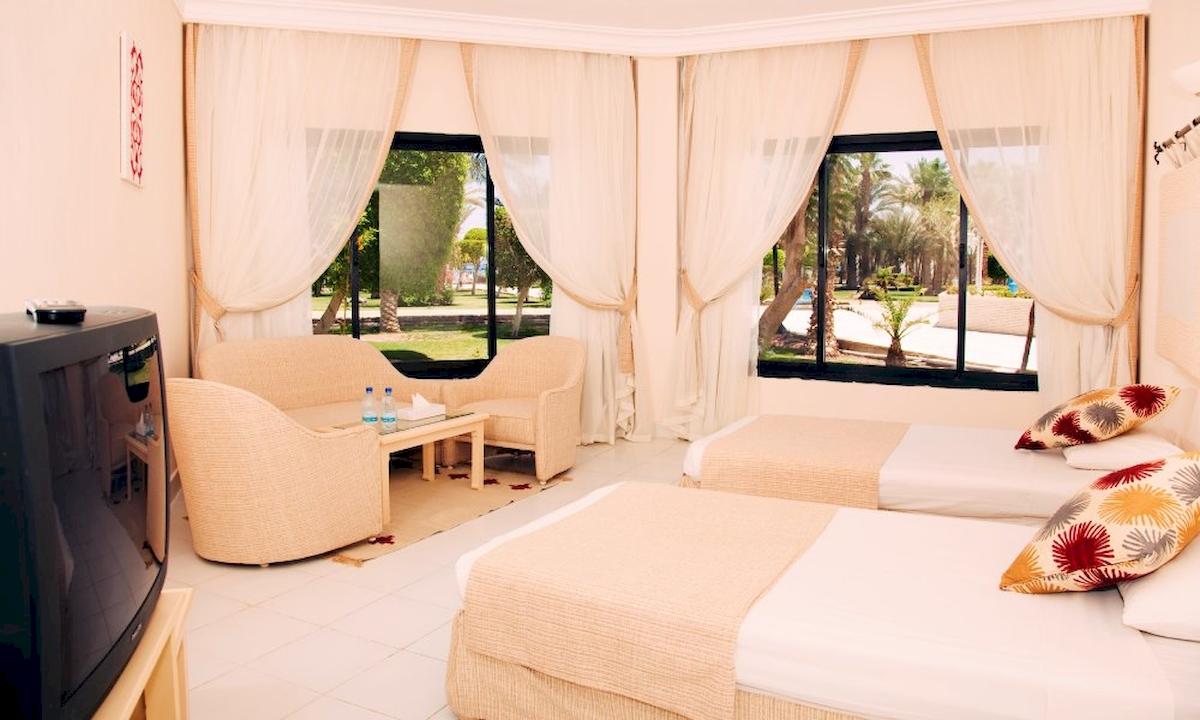 Zimmer im Grand Hotel Hurghada mit zwei Betten, einem Tisch und einem Fernseher.