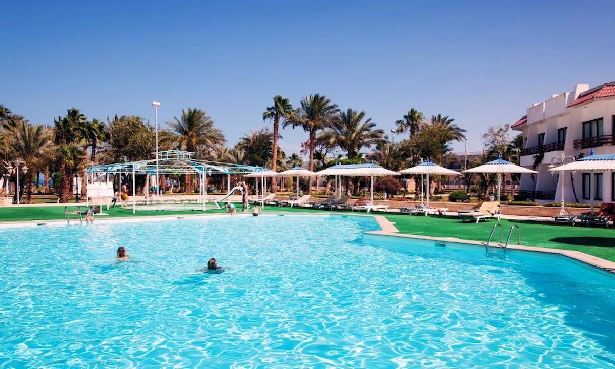 Außenpool des Grand Hotel Hurghada mit schwimmenden Gästen und Sonnenschirmen.