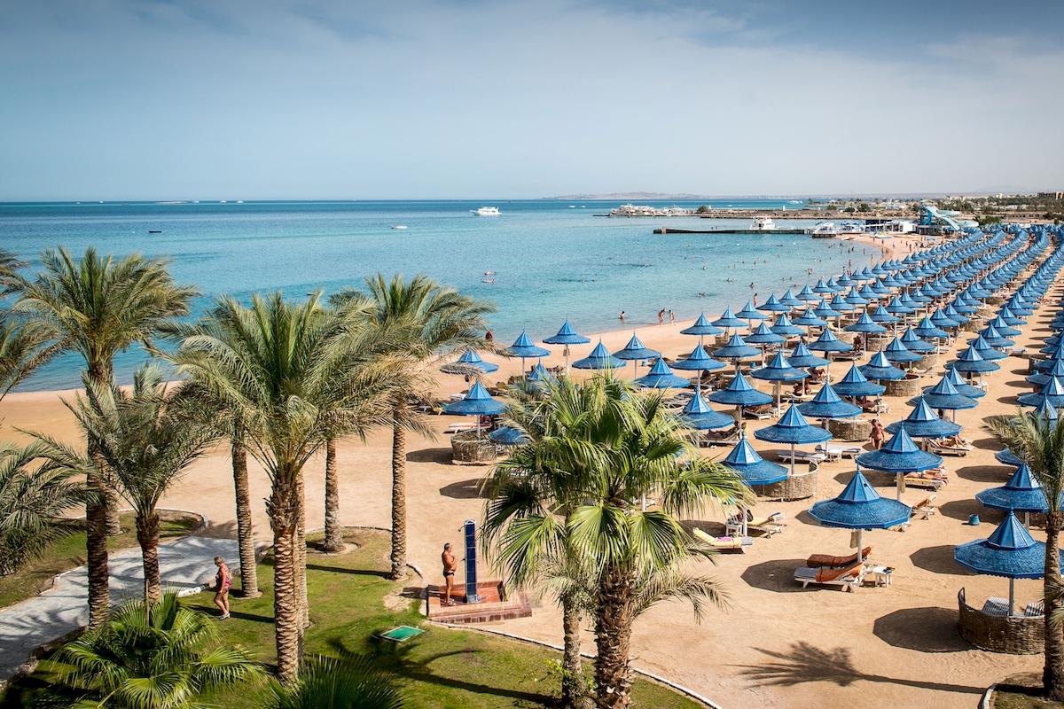 Strand des Grand Hotel Hurghada mit vielen Sonnenschirmen und Palmen
