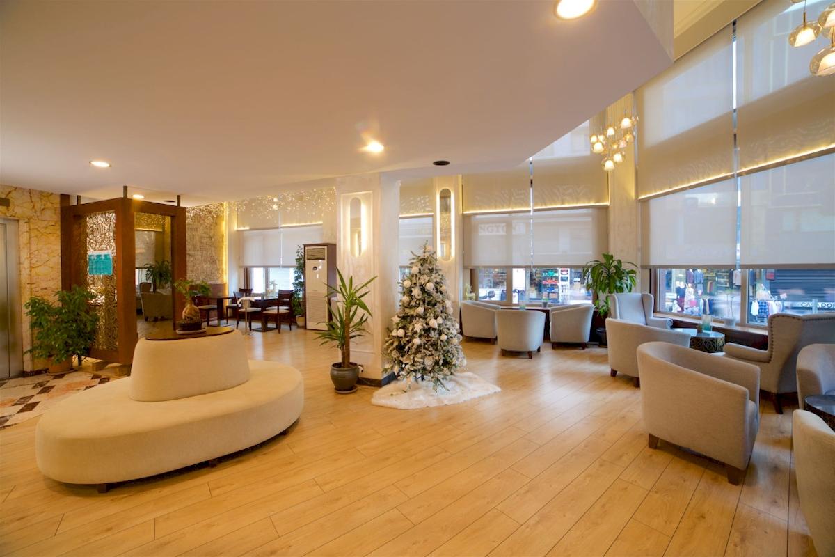 Empfangsbereich des Barin Hotels mit Holzboden, weißem Sofa, Weihnachtsbaum und Tischen.