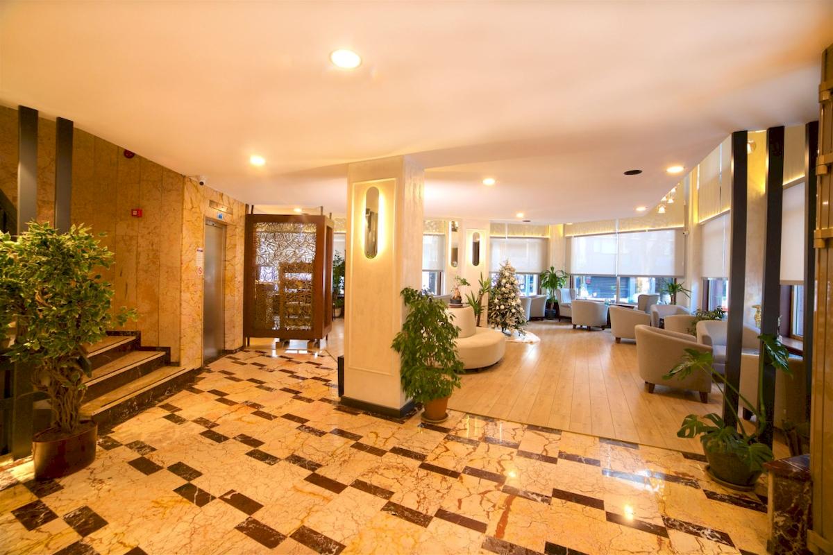 Empfangsbereich des Barin Hotels mit Marmorboden, Pflanzen und Sitzbereich.